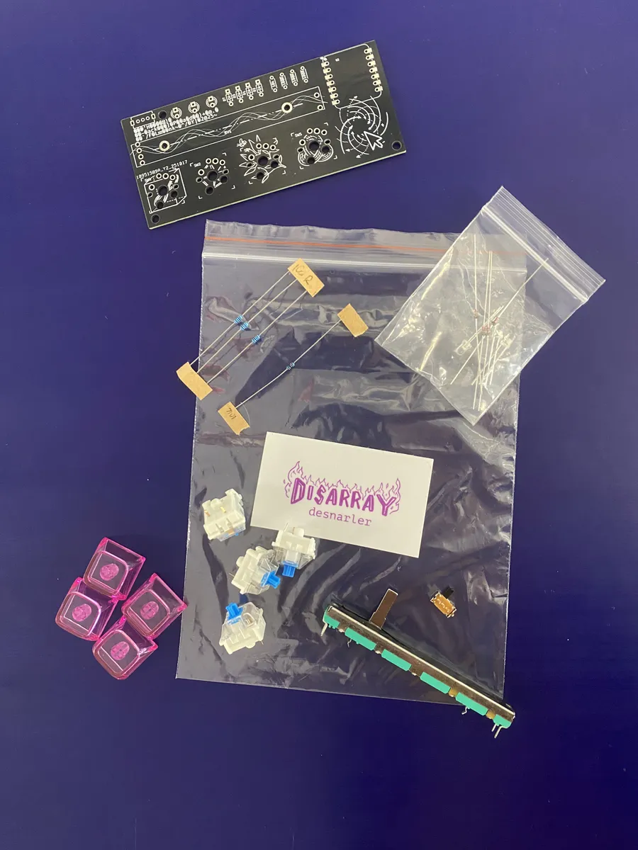 A Desnarler kit: the bare circuit board, bags of resistors and diodes, blue switches, pink keycaps, a slide fader and a Disarray desnarler card.