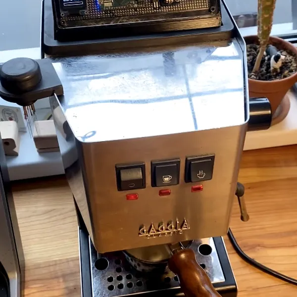 A Gaggia Classic espresso machine with the portafilter in place and a small circuit board with a display mounted on top.