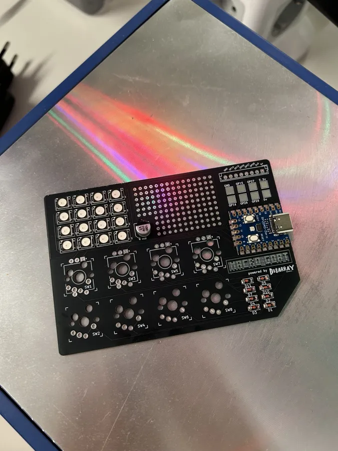 A bare black macro_GOAT circuit board with a 4×4 LED grid, a prototyping area, eight switch footprints and an RP2040-Zero soldered on.