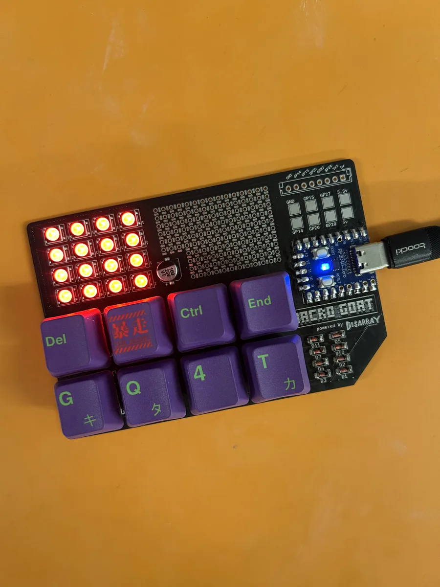 A macro_GOAT with eight purple keycaps and all sixteen LEDs lit red, plugged in over USB-C on an orange surface.