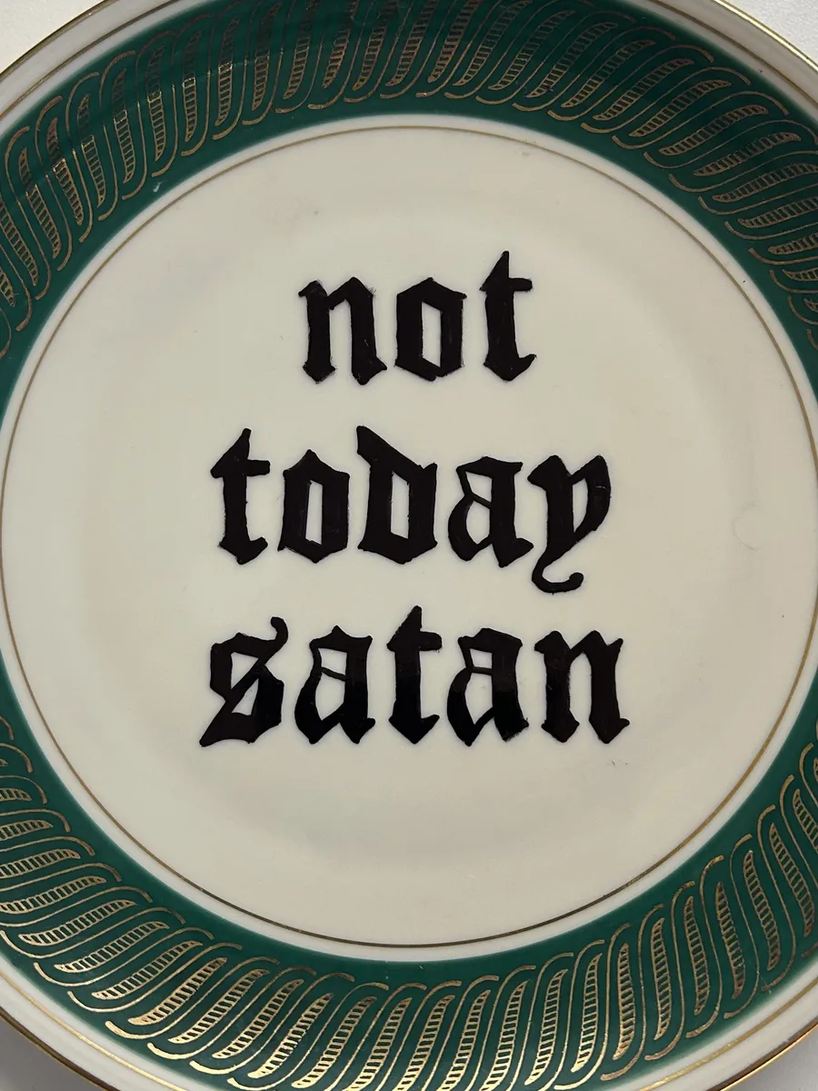 Close-up of the not today satan lettering on the plate with the green and gold border.